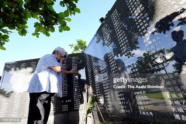 Woman sobs as she touches the names of her deceased family members engraved in the Cornerstone of Peace monument at a ceremony marking the 71st...