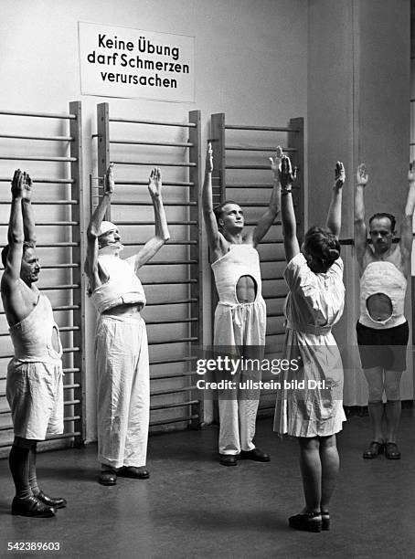 Krankengymnastik mit Patienten , die aufgrund von Wirbelverletzungen ein Gipskorsett tragen- 1943Aufnahme: Lothar Ruebelt