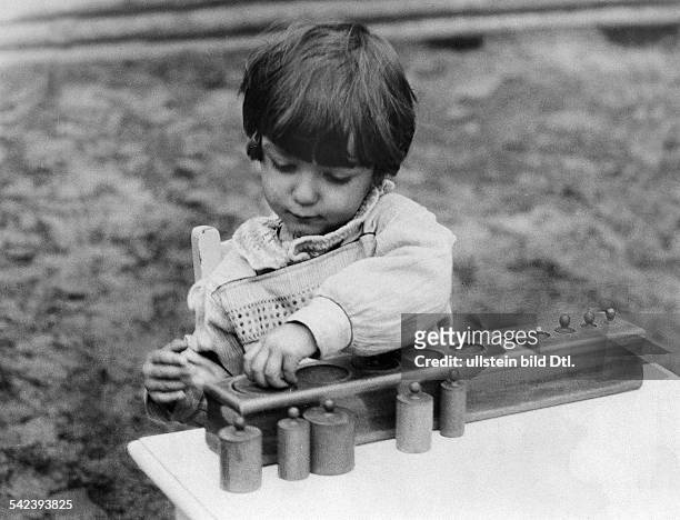Montessori - Schule in Berlin: Abschätzen von verschiedenen Gewichtsstücken und Einpassen in die richtigen Öffnungen- veröff. 1927Foto: Horlemann