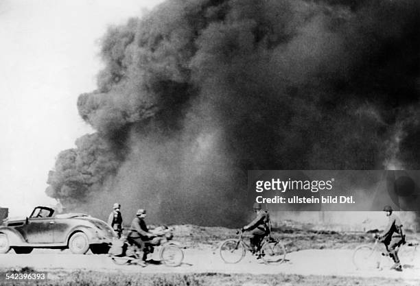Campaign in the west / battle of France 1940: : german bicycle patrol at Dunkirk - behind burning oil tanksEarly June 1940-