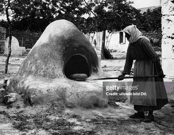 Baeuerin schiebt Brot in den Backofen imFreien in Corinth, Griechenland- 1934