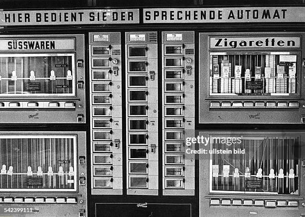 Verschiedene Süßwaren- und Zigarettenautomaten mit dem Schriftzug "Hier bedient Sie der sprechende Automat"- 1971