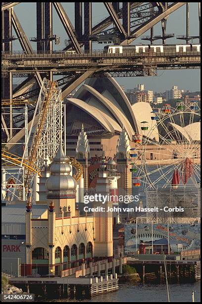 Fun fair at the foot of Harbour bridge with the Opera house in the background.