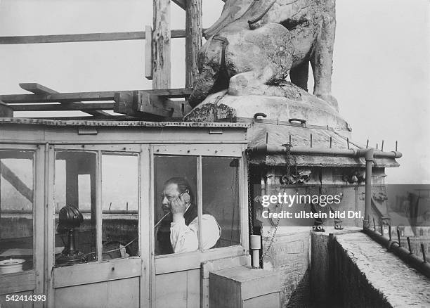 Ein Mann telefoniert in einem kleinen Raum über den Dächern von Paris- 1914