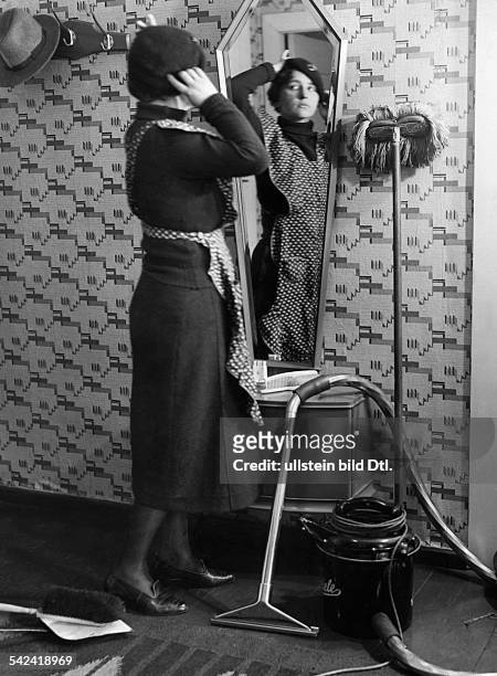 Frau mit Schürze vor dem Spiegel, r. Ein Miele Staubsauger- veröff. Sieben Tage, 12/1933