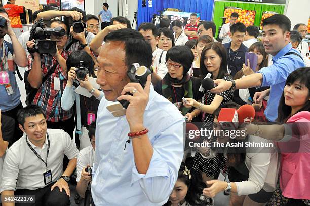 Hon Hai Precision Industry Chairman Terry Gou calls with 'RoBoHoN' humanoid robot mobile to promote Sharp's products after the annual shareholders...