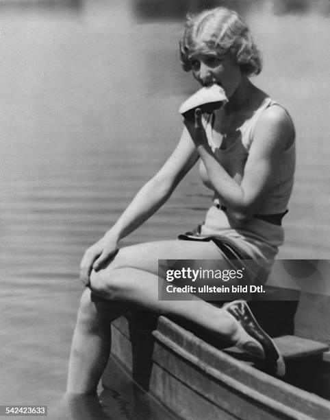 Nach dem Schwimmen" - eine junge Frau im Badeanzug sitzt auf einem Bootsrand und isst eine Scheibe Brot veröffentlicht: Uhu 9/1929 Foto: Martin...