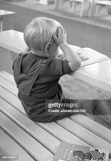 Kleiner Junge liest ein Buch und stützt seinen Kopf mit den Händen- 1958