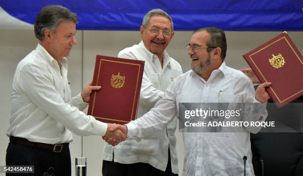 Colombia's President Juan Manuel Santos and Timoleon Jimenez, aka "Timochenko" , head of the FARC leftist guerrilla, shake hands accompanied by Cuban...