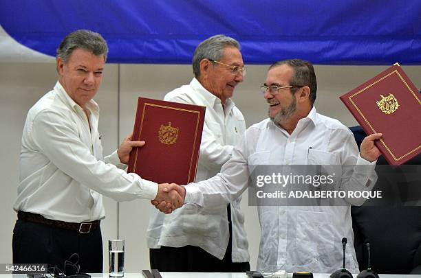 Colombia's President Juan Manuel Santos and Timoleon Jimenez, aka "Timochenko" , head of the FARC leftist guerrilla, shake hands accompanied by Cuban...