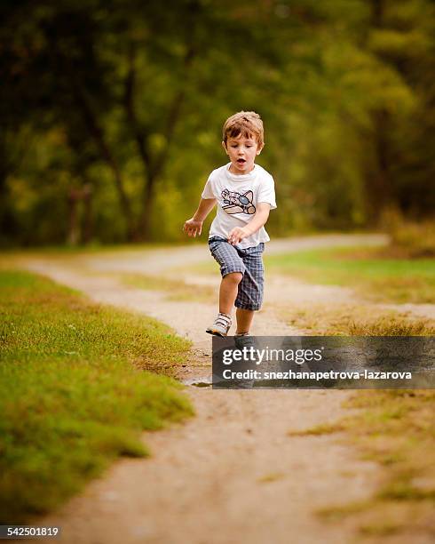 boy running along footpath about to jump over a puddle - boys jumping stock pictures, royalty-free photos & images