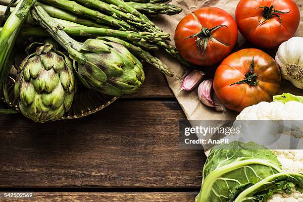 cauliflower, artichokes, asparagus, garlic and tomatoes on wooden table - alcachofra imagens e fotografias de stock