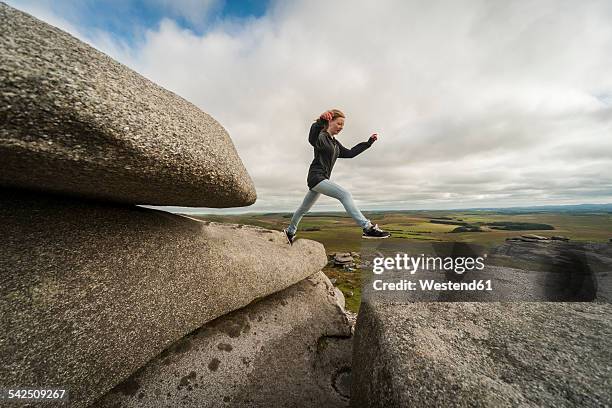 united kingdom, england, cornwall, bodmin moor, rough tor, rock formation, girl jumping - stone age - fotografias e filmes do acervo