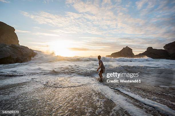 uk, england, cornwall, bedruthan steps, boy at the ocean - com os pés na água imagens e fotografias de stock