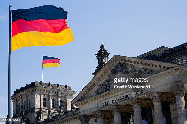 germany, berlin, view to upper part of reichstag building with two german flags - bundestag stock pictures, royalty-free photos & images