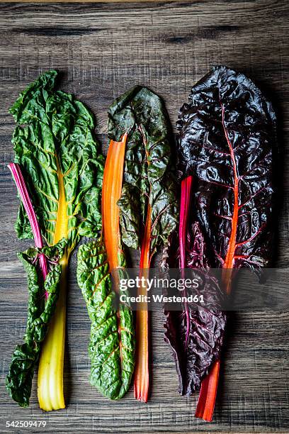 row of fresh chard leaves on dark wood - chard stock pictures, royalty-free photos & images