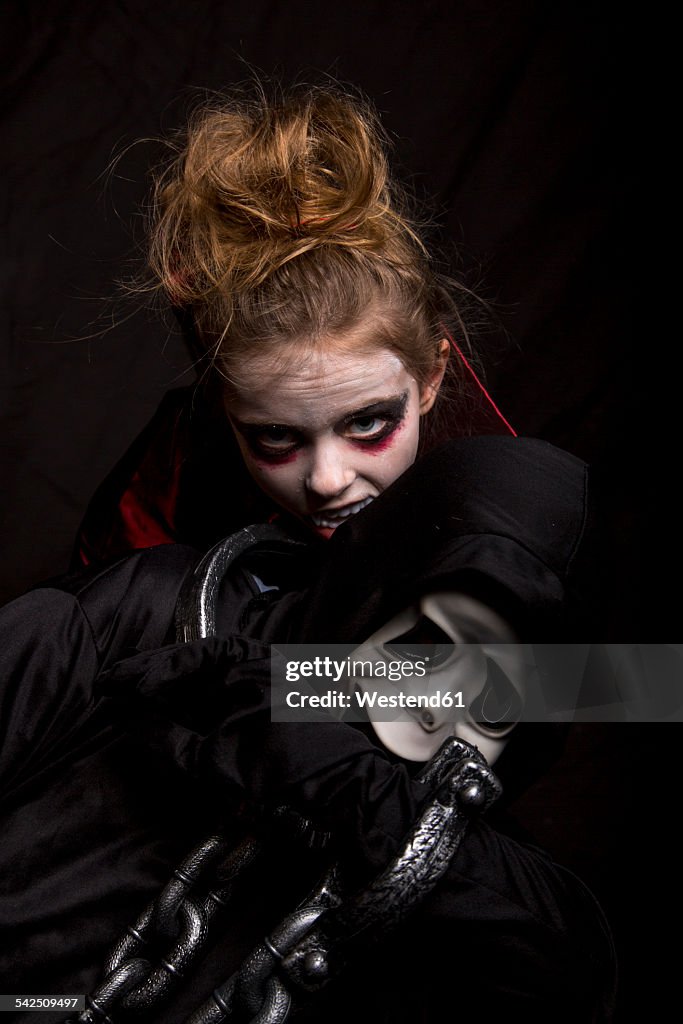 Girl masquarade as vampire biting boy wearing Scream mask