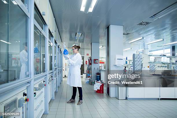 young female scientist with glass bulb in a chemical lab - onderzoeksfaciliteit stockfoto's en -beelden