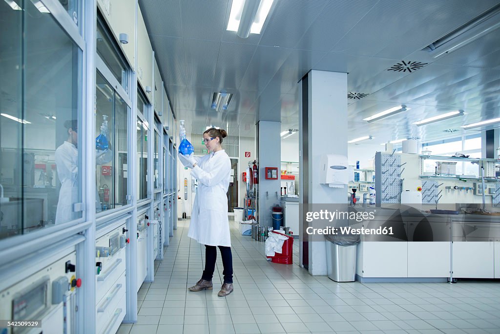 Young female scientist with glass bulb in a chemical lab