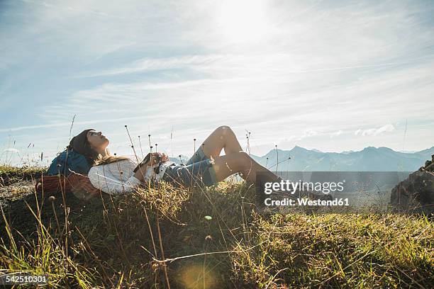 austria, tyrol, tannheimer tal, young hiker having a rest - lying on grass stock-fotos und bilder