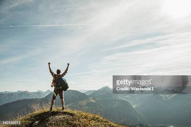 austria, tyrol, tannheimer tal, young man cheering on mountain top - anstoss stock-fotos und bilder