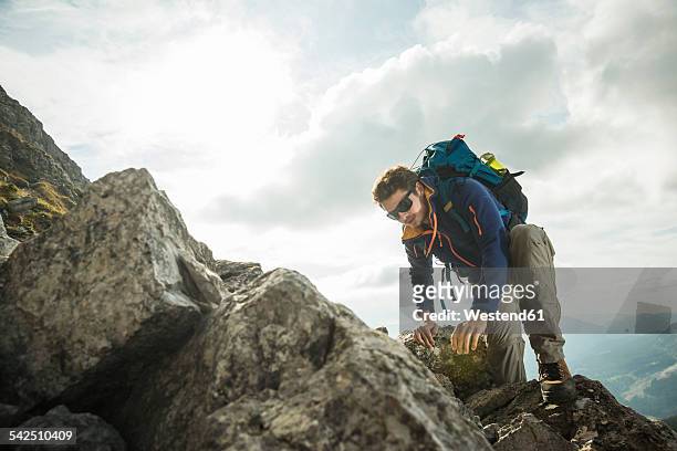 austria, tyrol, tannheimer tal, young man climbing on rock - rocky mountaineer stock pictures, royalty-free photos & images