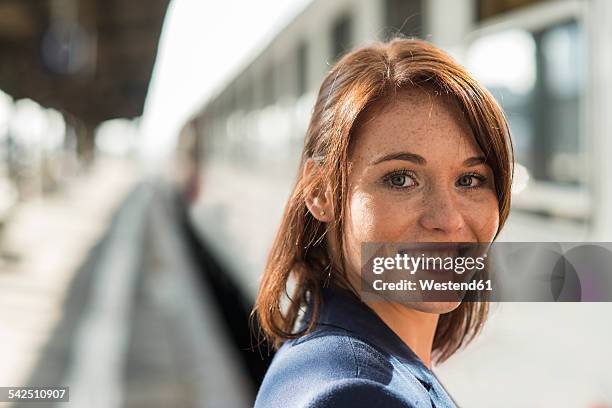 portrait of smiling brunette young woman outdoors - railroad station ストックフォトと画像