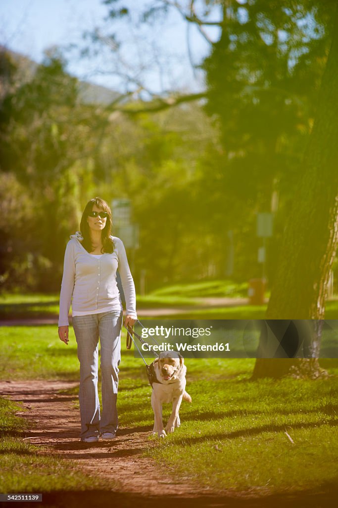 Visually impaired woman walking with guide dog in a park