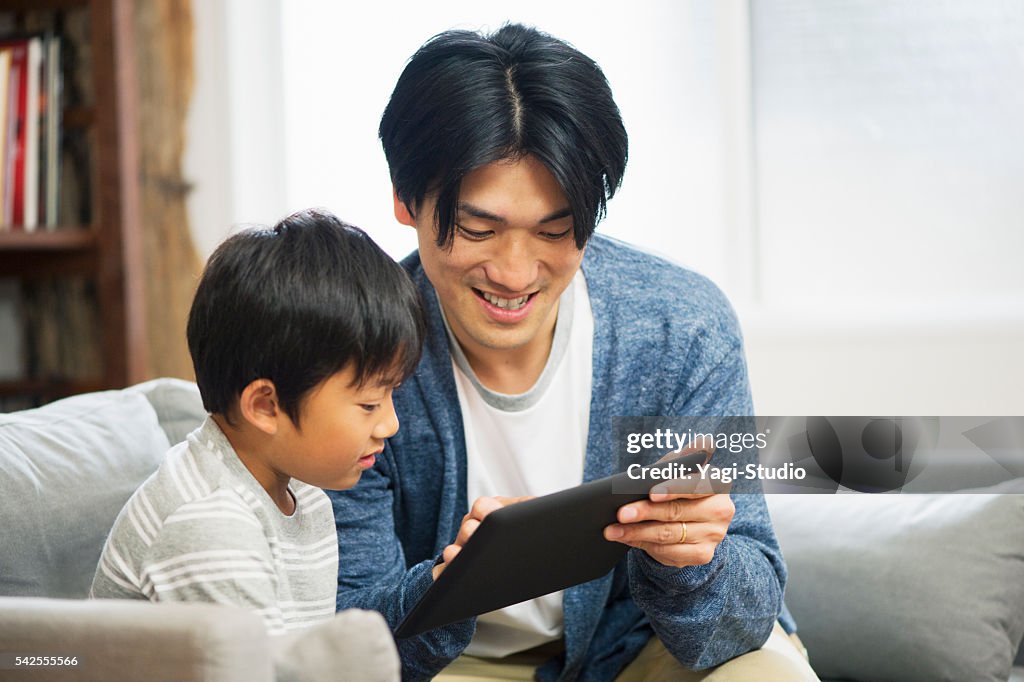 Father and son using digital tablet at home.