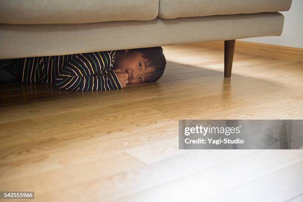 niño jugando esconden en el sofá - debajo de fotografías e imágenes de stock