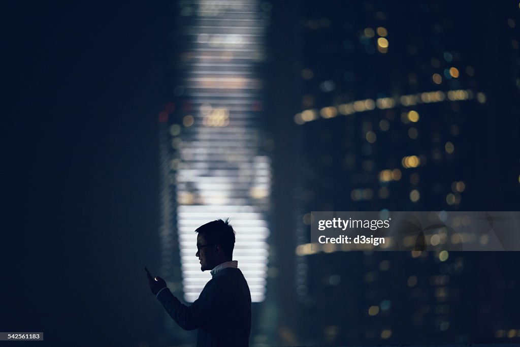 Silhouette of man using smartphone in city