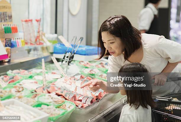 family choosing fresh fish in fish department - viswinkel stockfoto's en -beelden