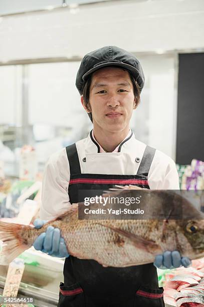 hombre sosteniendo un empleado de pescados y mariscos en el supermercado sección - pescadero fotografías e imágenes de stock