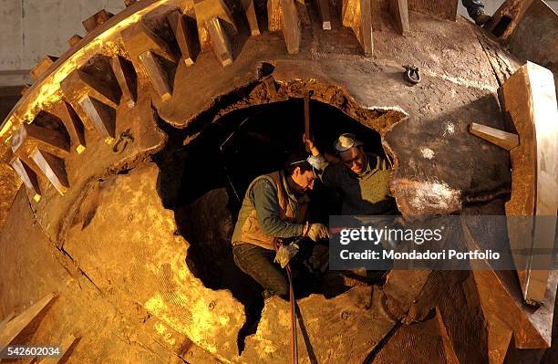 Some workers refining Italian sculptor Arnaldo Pomodoro's Grande Sfera, being created for the Exhibition in the Palais-Royal gardens in Paris. Milan,...