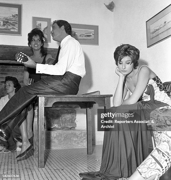 Italian songwriter Domenico Modugno playing a guitar under the gaze of Italian actress Antonella Lualdi on the set ofAppuntamento a Ischia. Italian...