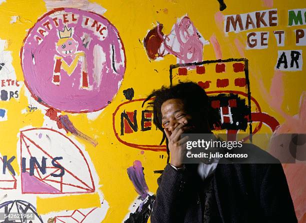 American artist, musician and producer of Haitian and Puerto Rican origins Jean-Michel Basquiat, in front of one of his paintings, during an...