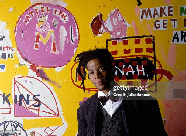 American artist, musician and producer of Haitian and Puerto Rican origins Jean-Michel Basquiat, in front of one of his paintings, during an...