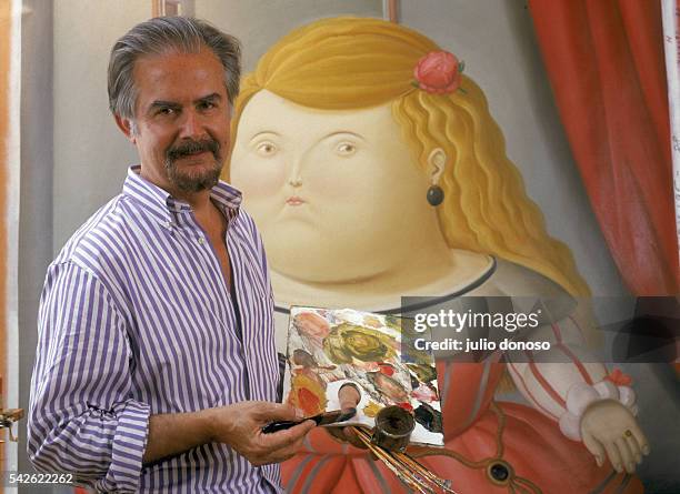 Colombian painter and sculptor Fernando Botero poses with one of his paintings in his Paris studio. Born in Medellin, Colombia, in 1932, Botero is...