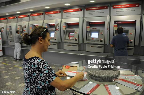 Patron prepares a deposit slip near ATMs at a Banco Santander SA bank branch in Sao Paulo. Banco Santander SA, is the Brazilian unit of Spain's...