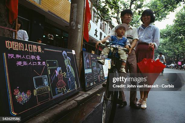 Couple with a single child stand near a government advertisment promoting China's family planning policy