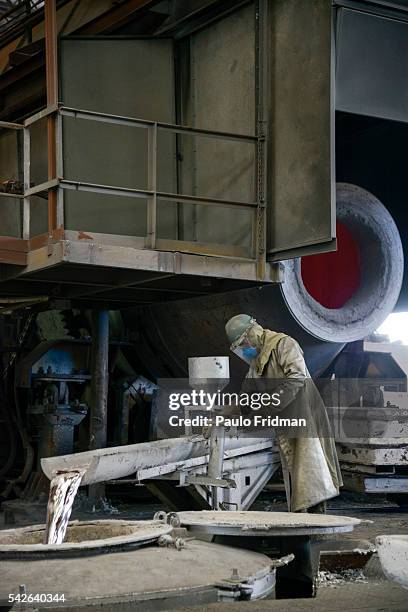 Worker monitors liquid aluminium as it flows into a vat during the recycling process at the at the Latasa Reciclagem SA collection center in...