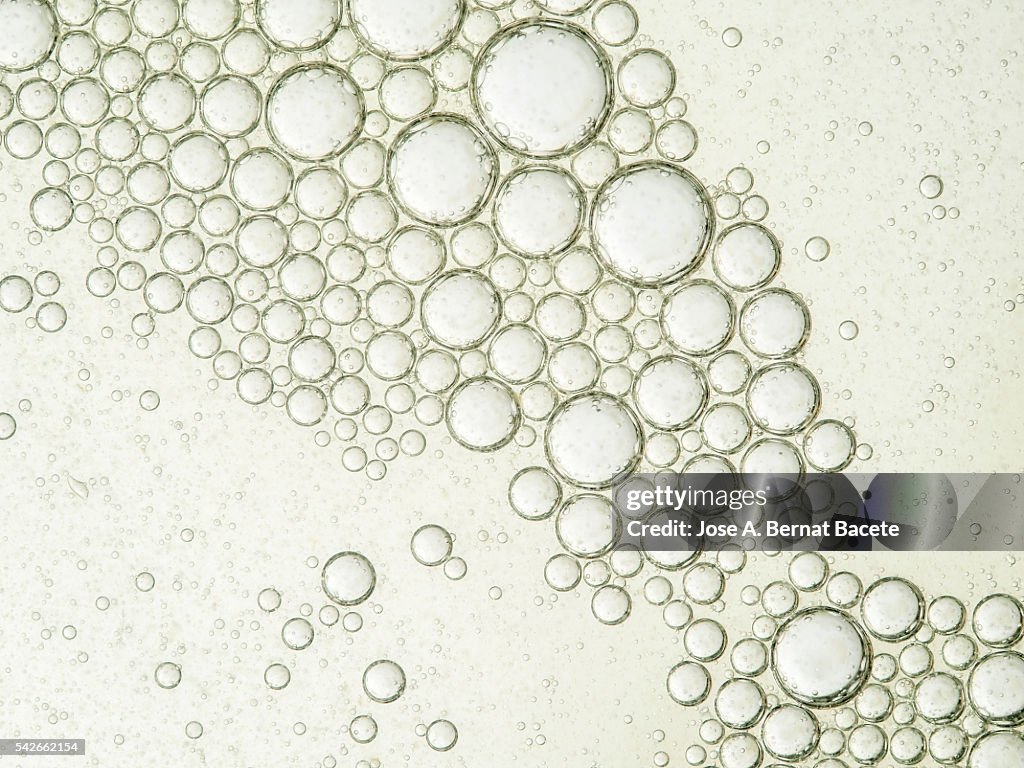 Oil drops and bubbles floating over water with a white background