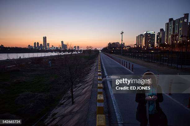 File photo taken on March 31, 2014 shows a woman checking a smartphone as she walks along the Han river in Seoul. Tired of endless text messages from...