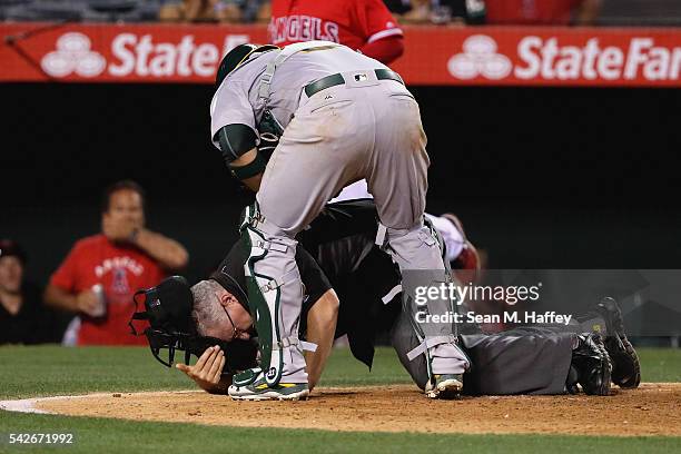 Umpire Paul Emmel falls to the ground as Stephen Vogt of the Oakland Athletics rushes to his aid after being hit by the bat of Jefry Marte of the Los...