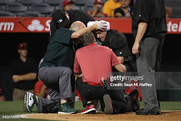 Umpire Paul Emmel is helped by trainers after being hit in the head by the bat of Jefry Marte of the Los Angeles Angels of Anaheim during the ninth...