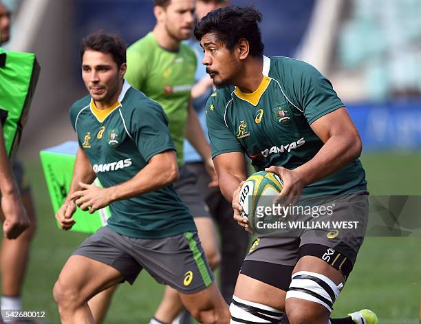 Australian rugby player Will Skelton is assisted by teammate Nick Phipps during the team's captain's run, in Sydney on June 24, 2016. / AFP / WILLIAM...