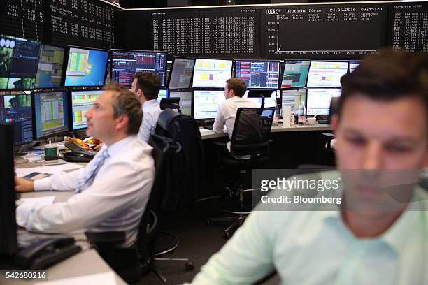 Financial traders monitor data as the DAX index curve is displayed beyond inside Frankfurt Stock Exchange following the U.K's European Union...