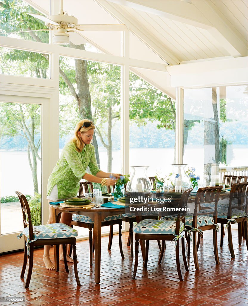 Woman setting dinner table with view of lake