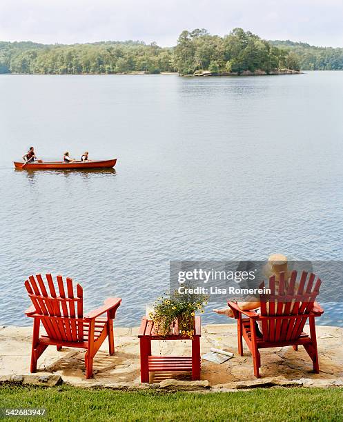 family canoeing on lake near bank with grass - family red canoe stock pictures, royalty-free photos & images