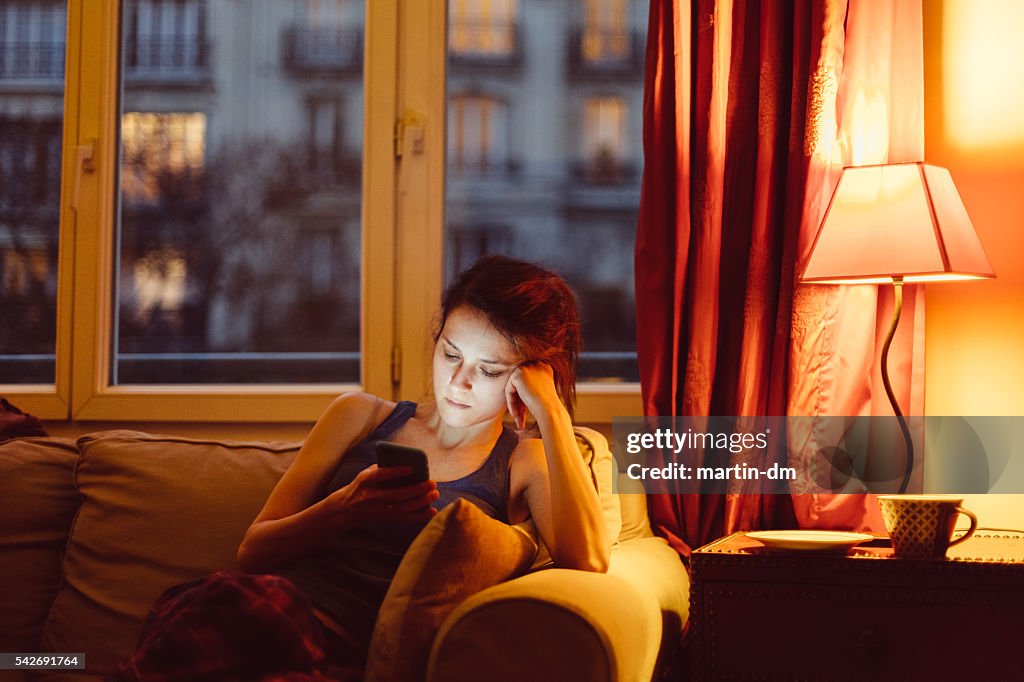 Mulher em casa mensagem de texto no telefone